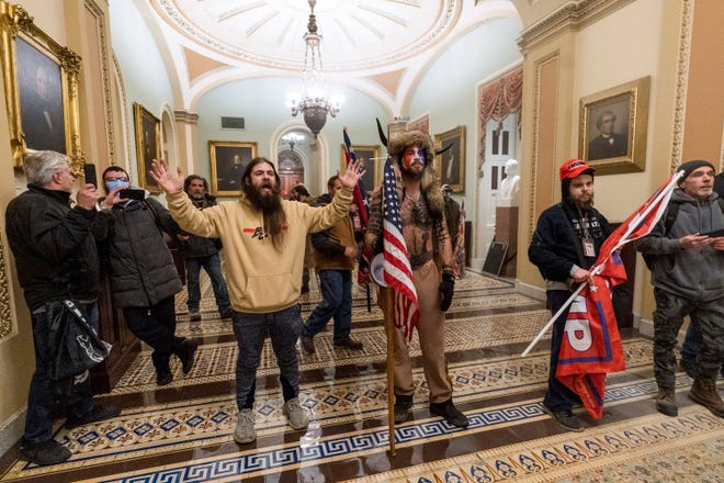 Supporters of President Donald Trump are confronted by U.S. Capitol Police officers outside the Senate Chamber inside the Capitol in Washington. Jacob Anthony Chansley, the Arizona man with the painted face and wearing a horned, fur hat, was taken into custody on Jan. 9 and charged with counts that include violent entry and disorderly conduct on Capitol grounds.