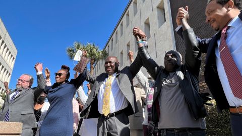 Arbery's family and their attorneys raise their arms in victory outside the federal courthouse in Brunswick, Georgia, after all three men involved in his killing were found guilty of hate crimes on February 22, 2022.