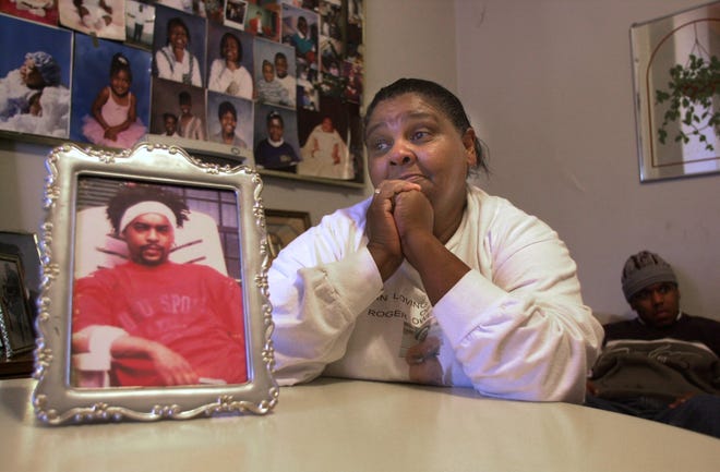 Essie Owensby, grandmother of Roger Owensby, Jr. (foreground photograph), reacts to the indictment of two Cincinnati police officers in her grandson's death while in police custody.