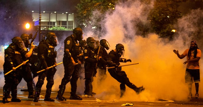 Scenes from a protest in downtown Louisville over the shooting of Breonna Taylor by Louisville police. A police officer kicks a tear gas canister back towards protesters after it was thrown past the police. May 28, 2020